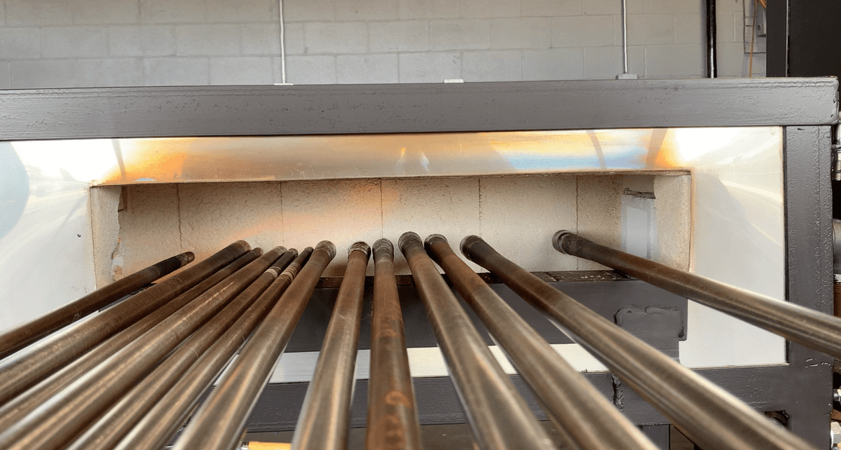 Metal pipes inside a kiln or furnace with a tiled wall background